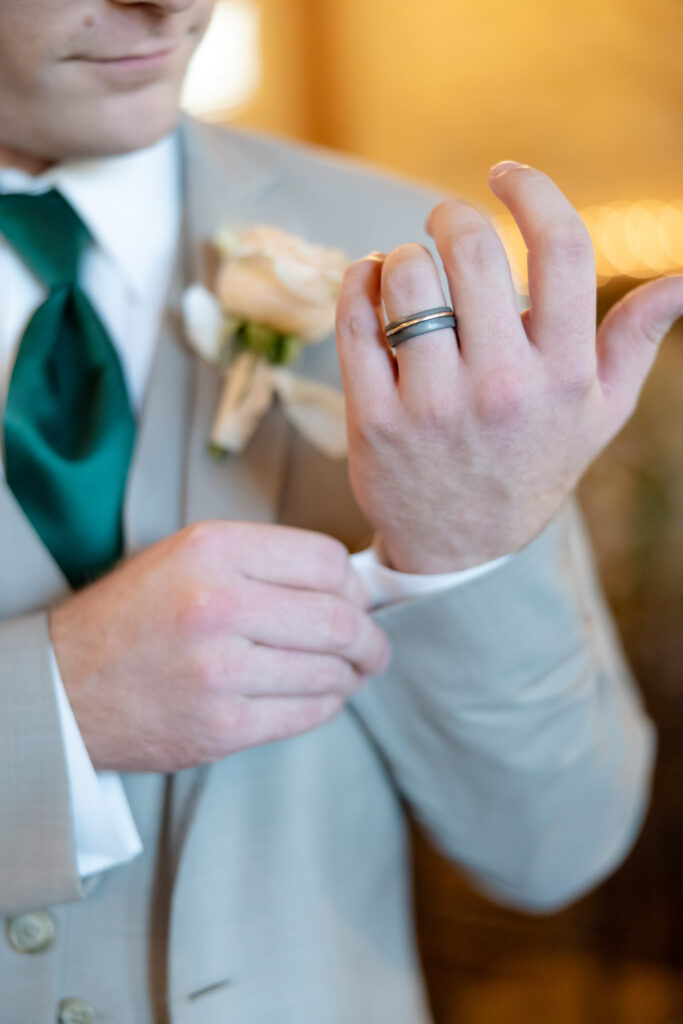Groom adjusting his shirt cuff and jacket with wedding ring visible before the ceremony, styled for Westchester weddings